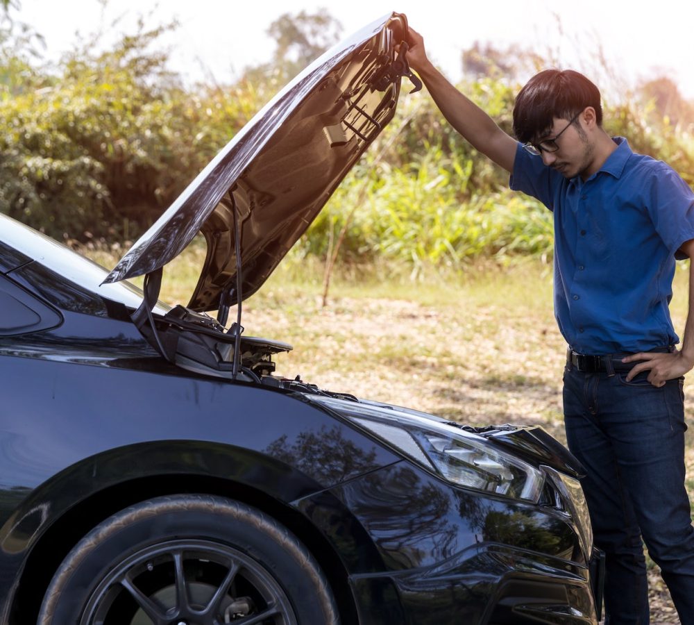 The car broke down, problem under the hood, the driver serious. man looks at the engine of the car.